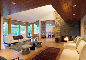Seating of all sorts in the upper-level living room is framed by quarter-sawn white oak flooring (with hydronic radiant heat), clear-finish tongue-and-groove cedar soffit beams with recessed lights, view-loving windows, and a fireplace where wood, raw stone, a slate hearth, and glass tile meet seamlessly. Light also floods in from the clerestory above. The furnishings are part of the homeowners’ collection of historical and classic furniture, art, and African textiles and artifacts.
