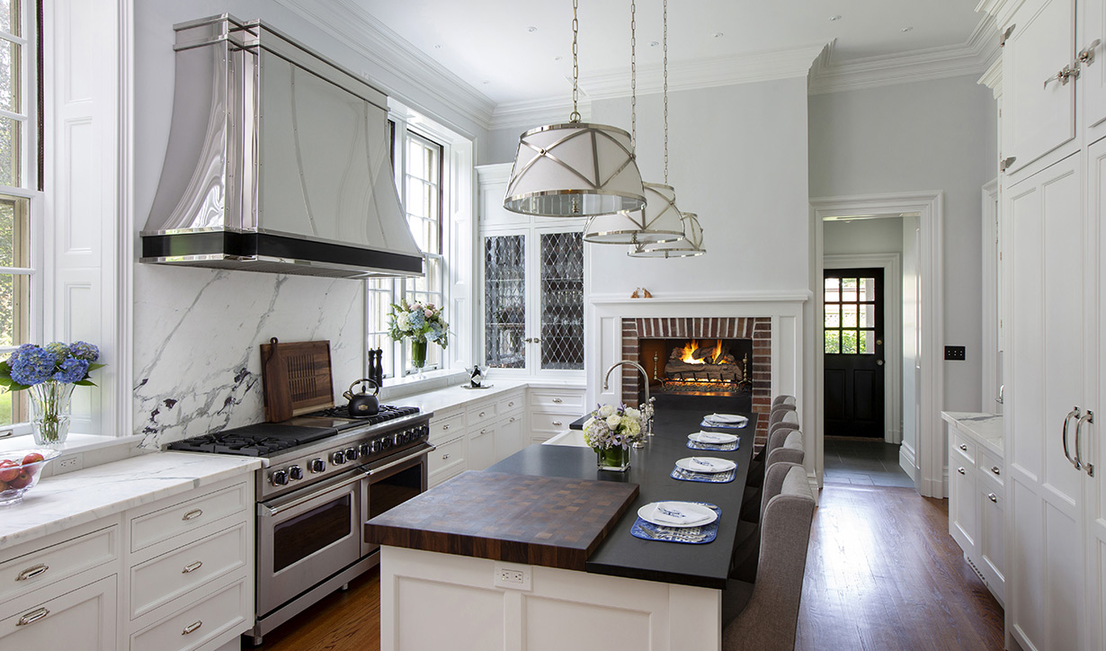 Leaded glass cabinetry doors in the kitchen and butler’s pantry beautifully echo the authentic leaded glass windows in the living room. The design team also uncovered an existing fireplace, which was elevated over two feet and converted to gas logs for enhanced visibility and warmth at the island height.